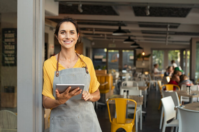 a restauranteur holding an iPad while smiling